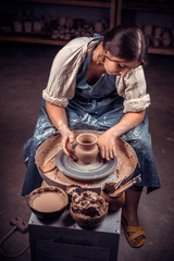 Stylish handicraftsman master making pottery, sculptor from wet clay on wheel. Artisan production.