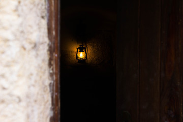 Ancient kerosene solitary lantern in a dark room through a slot in the door ajar. Loneliness, mystery, mysticism. Undergrounds and dungeons of Lviv, Ukraine.