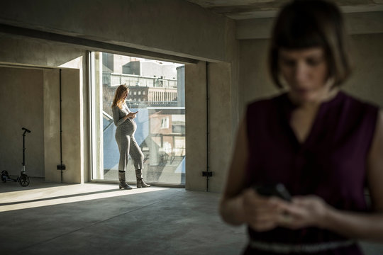 Two businesswomen checking messages on their smartphones