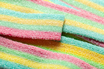 Yellow blue green and red striped jelly sweets sprinkled with sugar.