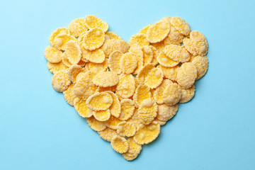 Yellow flakes in the shape of a heart on a blue background. I like breakfast cereal.