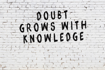 White brick wall with painted black motivational quote inscription