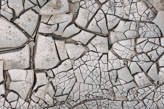 Dry gray cracked earth. Soil during the drought season. Background close up. The texture of the desert.