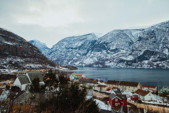 Amazing drone view of small settlement near tranquil sea and wonderful snowy mountain ridge on cloudy day
