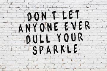 White brick wall with painted black motivational quote inscription