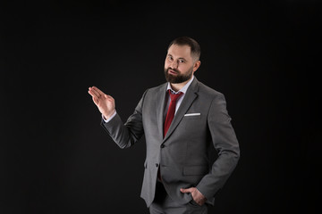 portrait of young handsome business man presenting gesture on black background