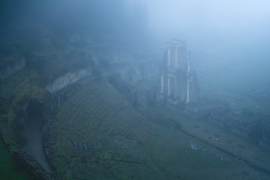 From above view of mossy green ruins in heavy fog, Italy