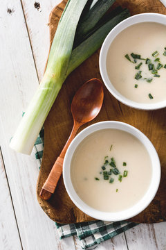 Shoot from above of two bowls of tasty Vichyssoise soups on wooden table with leek