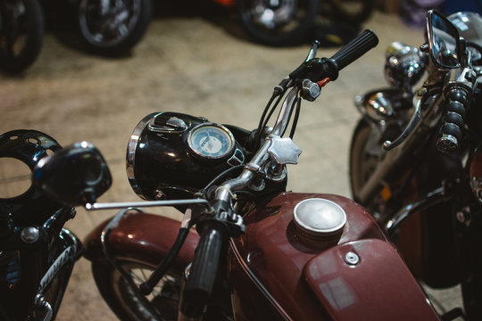 Shabby vintage motorbikes with broken headlights parked inside repair workshop