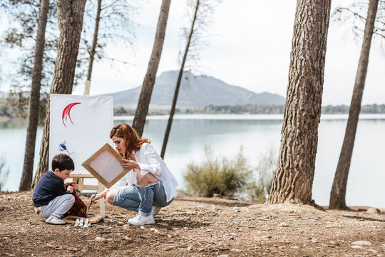 Mother and boy painting near lake