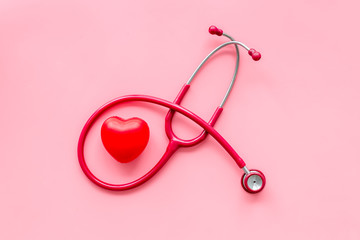 Stethoscope and heart for family doctor set to cure of cardiac disease on pink background top view