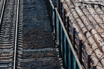 Cars loaded with logs are on the railroad tracks.