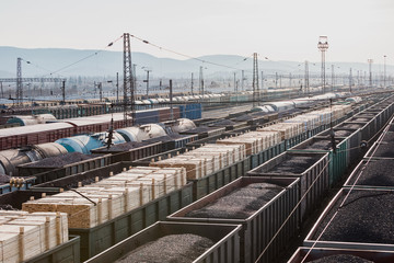 Obraz premium A lot of cars are on the railroad tracks. Freight trains. Freight shipping. Coal, wood planks, gravel, crushed stone. Wagons. Railway carriage.