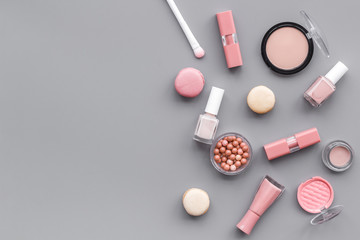 decorative cosmetics for make-up with macaroon cookies on gray tabletop background space for text