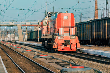 The locomotive moves along the railway track at the station.
