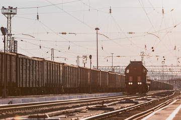 The locomotive moves along the railway track at the station.