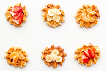 Breakfast with Belgian waffles with strawberry, tangerine and banana topings on white background top view