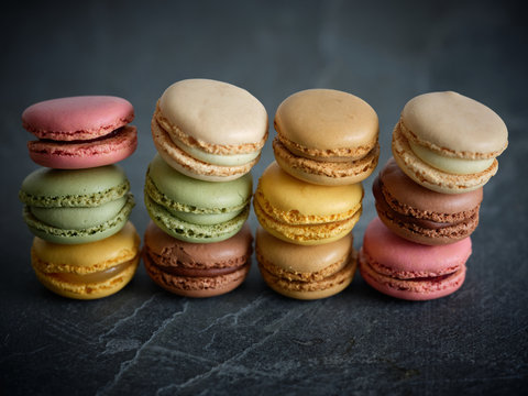 piles of bright fresh tasty macaron biscuits on grey board