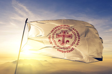 Albanian Orthodox Church flag waving on the top sunrise mist fog