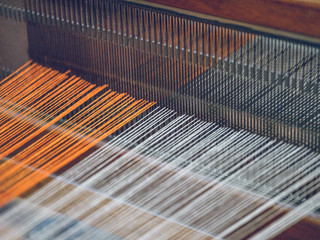 Cotton threads of orange and white color on industrial loom on fabric factory