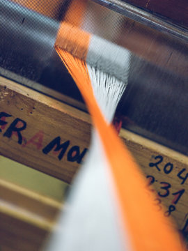 White and orange threads on loom