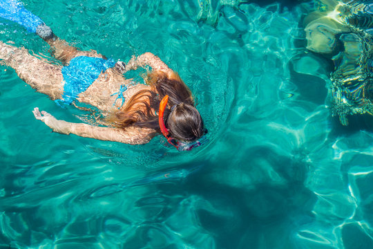 swimming girl in bright colorful aquamarine water of Gulf of Aqaba in Red sea, summer vacation and activities concept wallpaper pattern picture with empty copy space for text or inscription