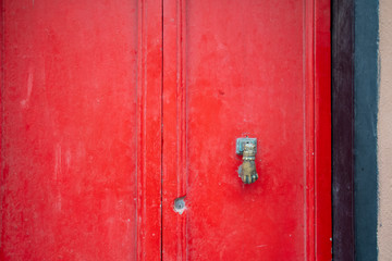 Close-up of an old wooden red door with a vintage knob in the shape of a female hand, Sestri Levante, Liguria, Italy