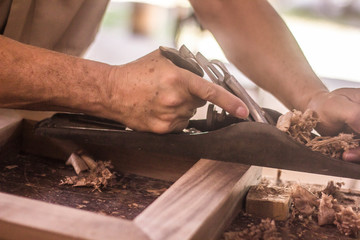 carpenter cutting plank with saw