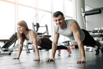 Fototapeta premium Sporty young couple doing plank exercise in gym