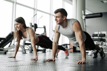 Sporty young couple doing plank exercise in gym