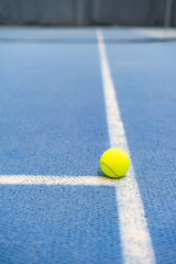 Tennis ball indoor on tennis court, white line, blue surface, copy space