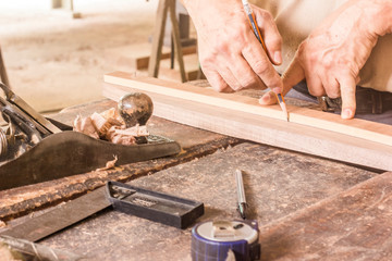 carpenter cutting plank with saw