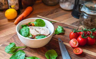Salad bowl of vegetables, beans and piece of chicken in the kitchen for preparing the veggie meal.