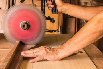 carpenter cutting wooden plank with saw