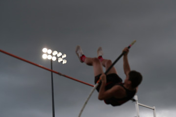 A high school athlete participates in the pole vault.