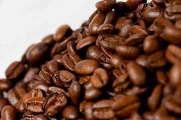 Freshly ground coffee beans roasted with fruits of coffee plant, on white background.