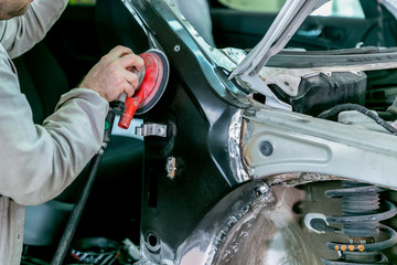 Car repair in car service. Mechanic worker repairman sanding polishing car body and preparing automobile for painting during repair and renew at service station shop
