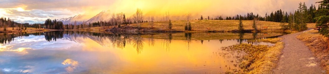 Wide Panoramic Springtime Mountain Landscape and Dramatic Sunset Colors at Quarry Lake above City of Canmore in Alberta Foothills of Canadian Rockies near Banff National Park © Autumn Sky