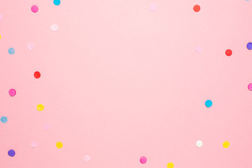Multi-colored confetti on pink color paper background with space for text . Flat lay composition...