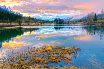 Springtime Mountain Landscape and Dramatic Sunset Colors at Quarry Lake above City of Canmore in...