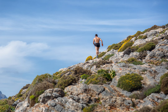 Running people - male runner at sunset in mountain. Man athlete jogging training for marathon trail run in beautiful amazing landscape nature above the clouds. Fit shirtless male cross country runner.