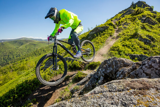 Professional athlete is riding enduro bicycle on a beautiful rocky trail.