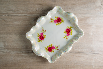 white pearl color porcelain vintage tray with painted flowers on a wooden table