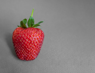 Red strawberry on a gray paper background. Horizontal banner, copyspace. View from above. Natural food, healthy food.