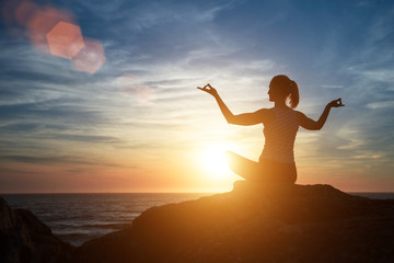 Yoga silhouette of meditation woman on the beach at amazing sunset.