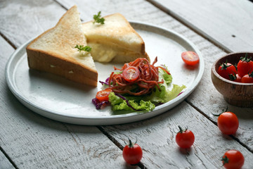 Fototapeta na wymiar Toast sandwich and vegetables salad in a white plate on white wood table