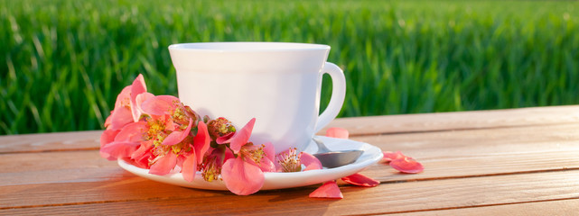 Mug with tea on the table in the green field