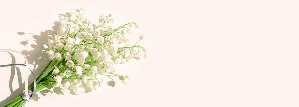 A bouquet of lilies of the valley on a pink background. Isolated, selective focus, copy space. Banner