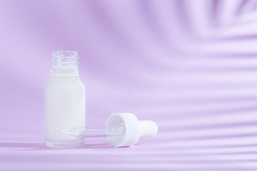 Natural cosmetics: serum with dropper on lilac background with shadow.