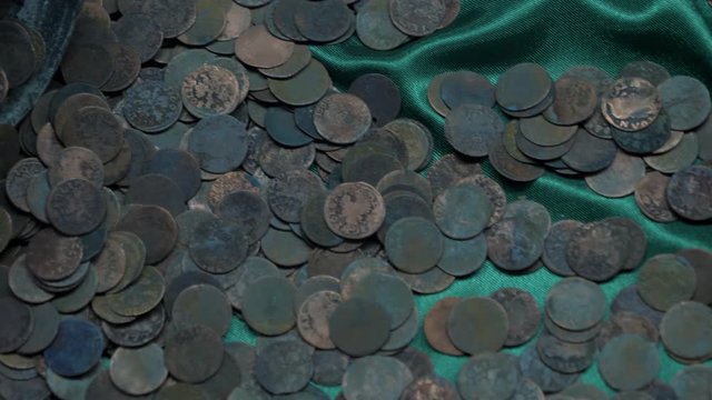 rusty old coins are lying on a green cloth
